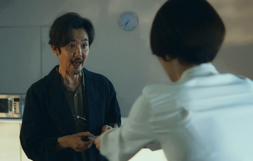 ドラマ「エルピス―希望、あるいは災い―」第６話、斎藤正一（鈴木亮平）からのメッセージを放送終了後に見るからと、携帯を村井喬一（岡部たかし）に預ける浅川恵那（長澤まさみ）