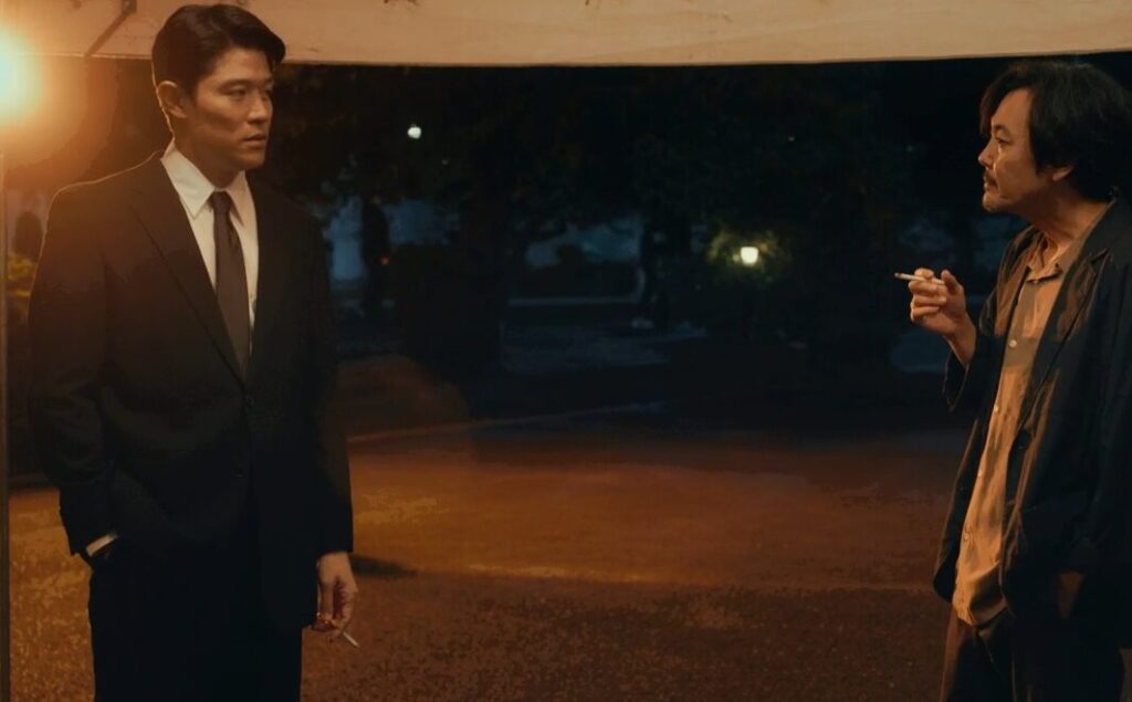 ドラマ「エルピス―希望、あるいは災い―」第９話、大門亨（迫田孝也）の葬儀場、喫煙所で向かい合う斎藤正一（鈴木亮平）と村井喬一（岡部たかし）