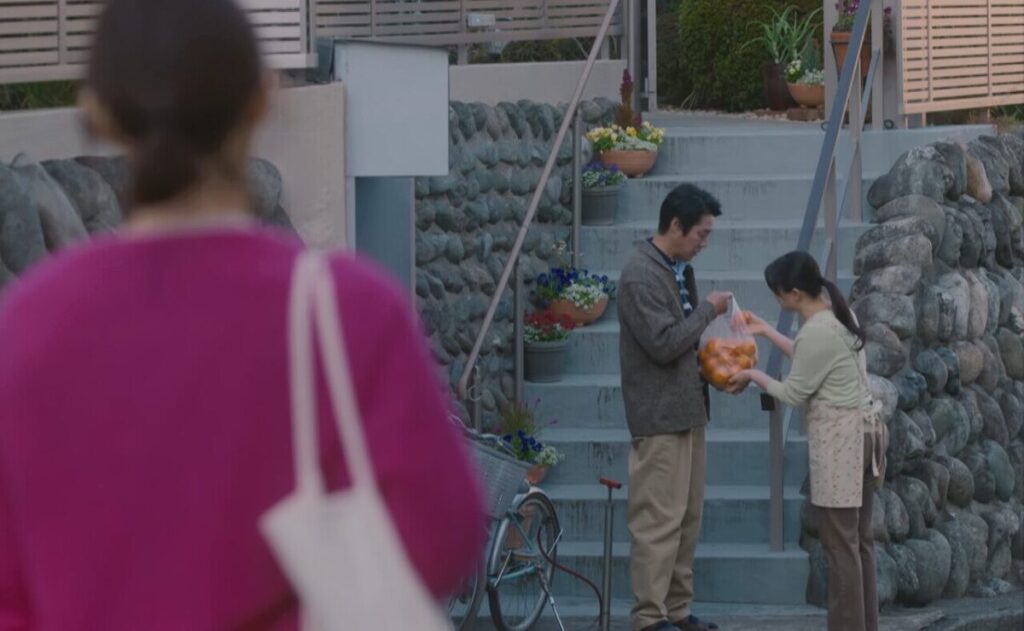 ドラマ「妻、小学生になる。」第２話、近所の主婦からみかんをもらっている新島圭介(堤真一)と遠くから見ている新島貴恵（石田ゆり子)