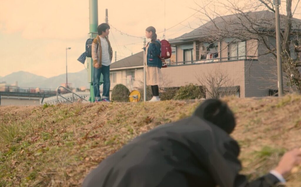 ドラマ「妻、小学生になる。」第２話、白石万理華（毎田暖乃）とタケル（川口和空）が土手で話しているのを陰から見ている新島圭介(堤真一)