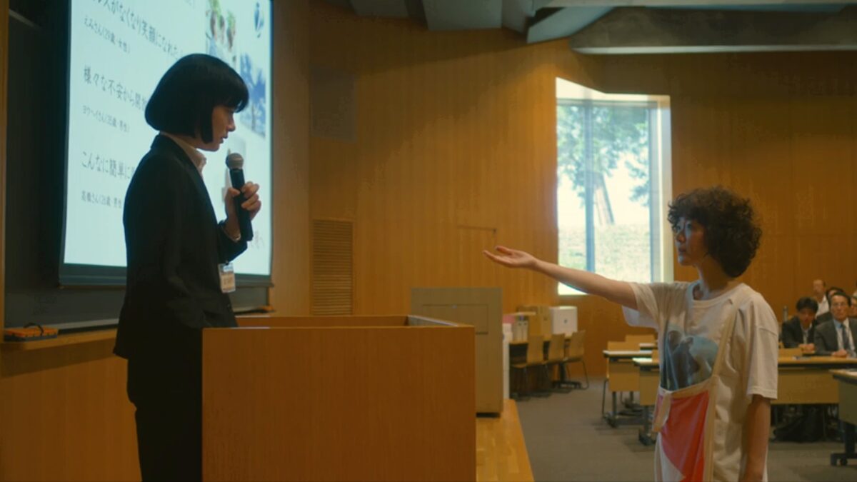 ドラマ「凪のお暇」第６話、会社のセミナー会場で司会をしている坂本龍子（市川実日子）に黙って手を差し伸べる大島凪（黒木華）