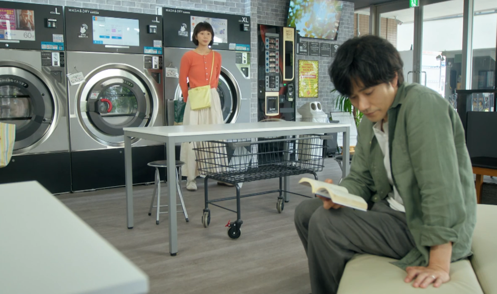 ドラマ「Tシャツが乾くまで」第7話、コインランドリーで本を読んでいる瀬尾充（松山ケンイチ）に話しかけたそうにしている園田あずさ（夏帆）