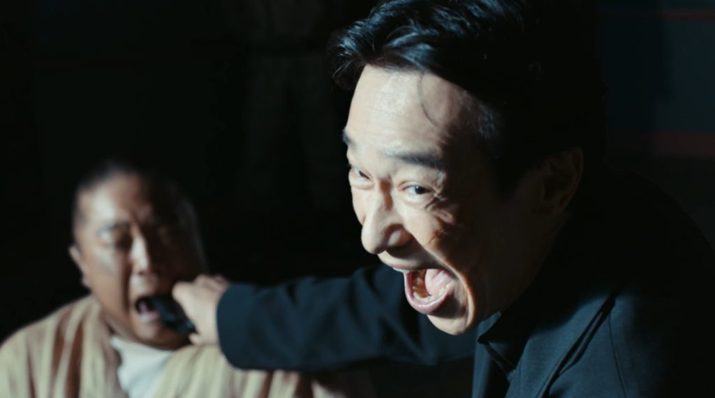 ドラマ「VIVANT・第2シーズン」第17話、ドラムの口に銃口を突っ込んでいる劉銘軒（リュウ・ミンシュエン／堺雅人）